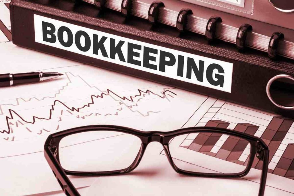 Bookkeeping binder with reading glasses and printed financial reports